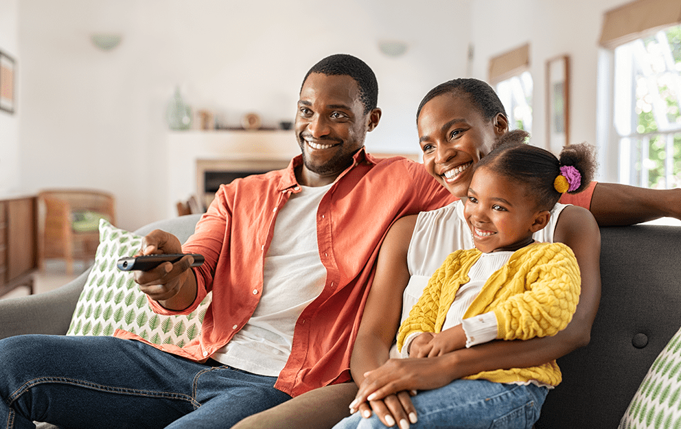 Happy family watching TV together in their living room.