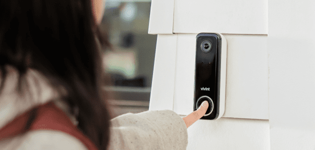 Person pressing a smart doorbell button.